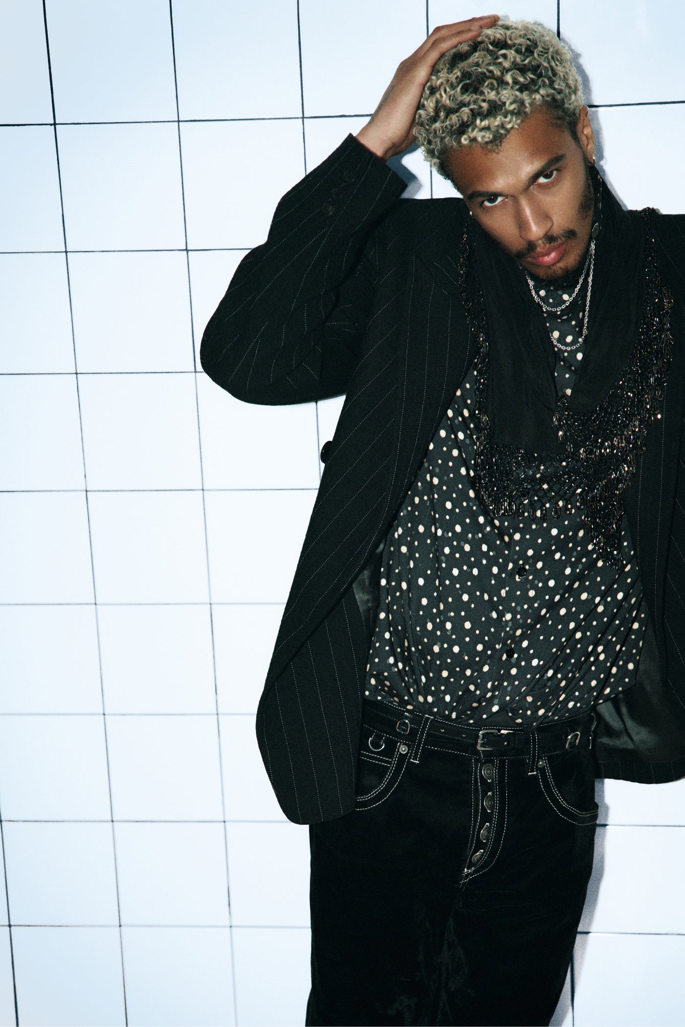 Men model wearing black outfit with a vest, shirt and denim pants.